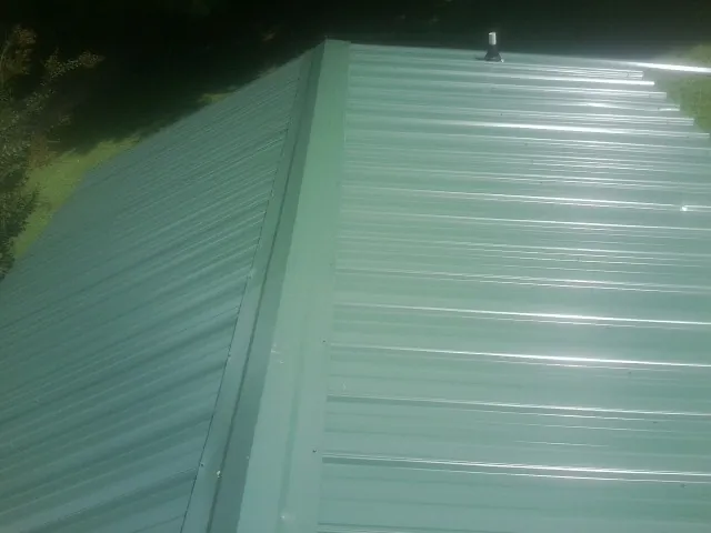 New green metal panels meeting at the ridge of a roof — Flat Roof Repair work by our crew in Annapolis Junction