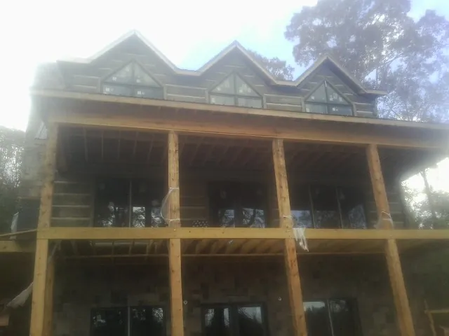 Dormers and porch framing on a large log home under construction — Roof Coating work by our crew in Annapolis Junction