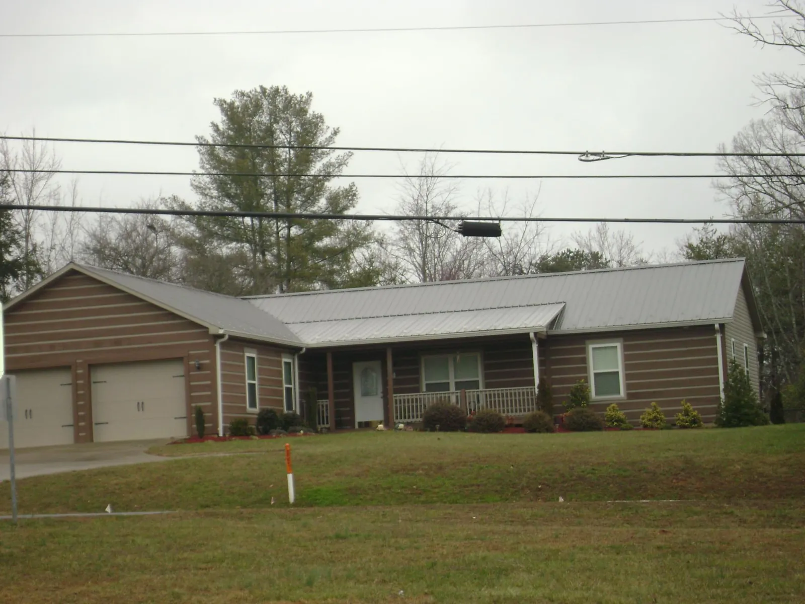 Gray metal roof on a log sided ranch home with a front porch in Annapolis Junction
