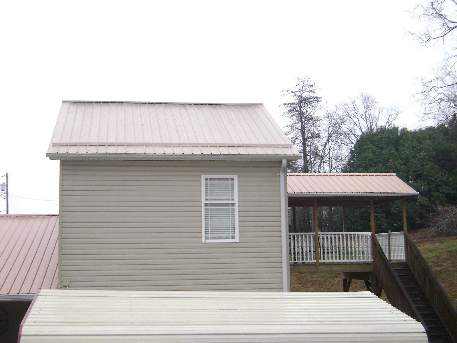 Tan metal roofs on a two story addition and attached porch, from a Roof Replacement job in Annapolis Junction