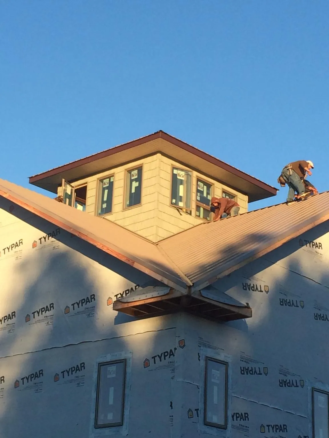 Roofers working around a rooftop cupola on a new metal roof at sunset — Roof Waterproofing in Annapolis Junction by Roofing Brothers
